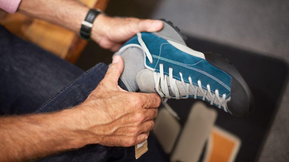 Unrecognizable senior man in sports and outdoor equipment store choosing to buy hiking shoes.