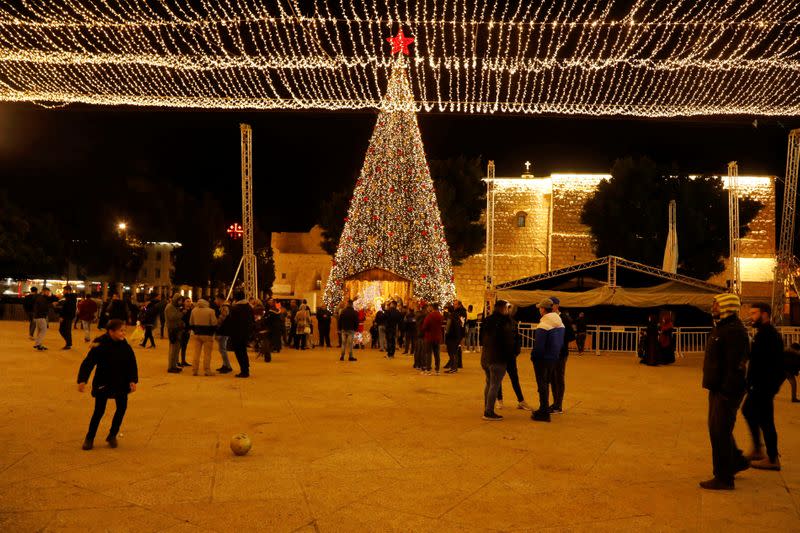 A girl plays with a ball as people stand at Manger Square in Bethlehem in the Israeli-occupied West Bank