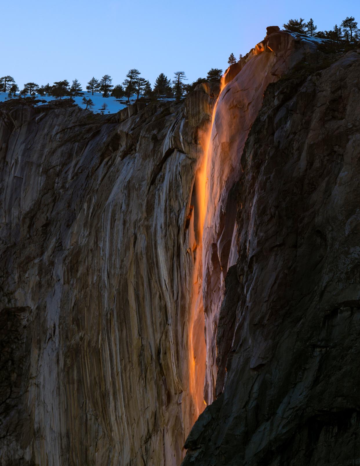 Horsetail Fall glows Monday, February 13, 2023 as light from the setting sun strikes El Capitan in Yosemite National Park. Weather permitting, the event occurs every year when the sun sets in the right spot of the horizon to shine directly onto El Capitan for about ten minutes at the end of each day. Best viewing is in the last two weeks of February. The light strikes El Capitan the same way in October but the snow caps that feed the fall are dry. Reservations are required to drive into the park on Fridays, Saturdays and Sundays through the month of February.