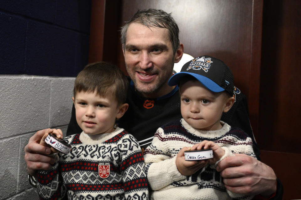 Washington Capitals left wing Alex Ovechkin, center, poses with his children Sergei, left, and Ilya, right, and the pucks he scored goals 801 and 802 after an NHL hockey game against the Winnipeg Jets, Friday, Dec. 23, 2022, in Washington. (AP Photo/Nick Wass)