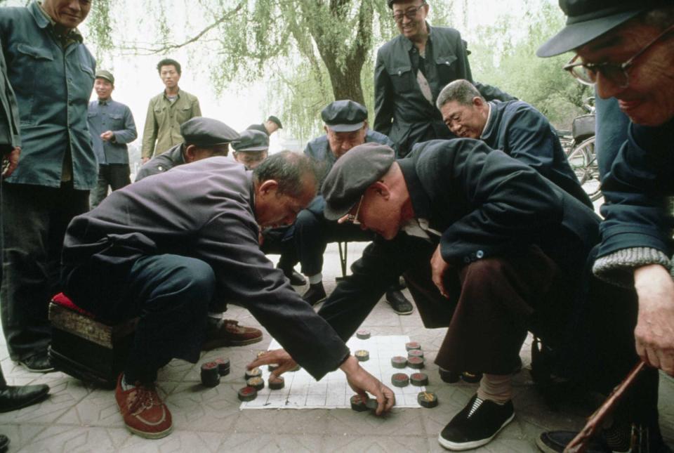 1989年4月日，北京的一個公園裡，一群人圍著兩個下象棋的男人。 歐洲象棋就是源於這種古老的遊戲。攝： Turnley/Corbis/VCG via Getty Images