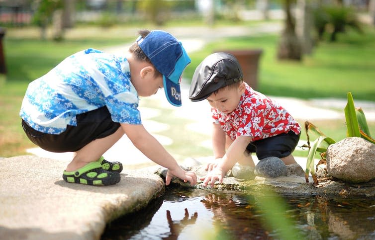 Two children play by water