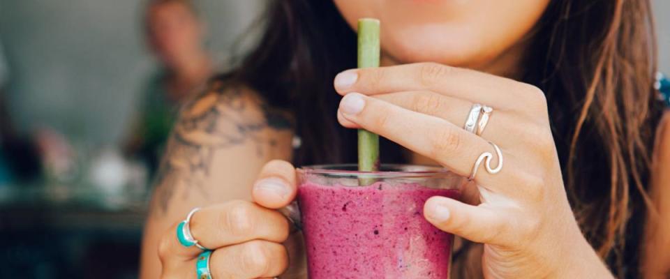 Young girl having a good morning healthy breakfast smoothie drink made of super foods, fruits, nuts, berries