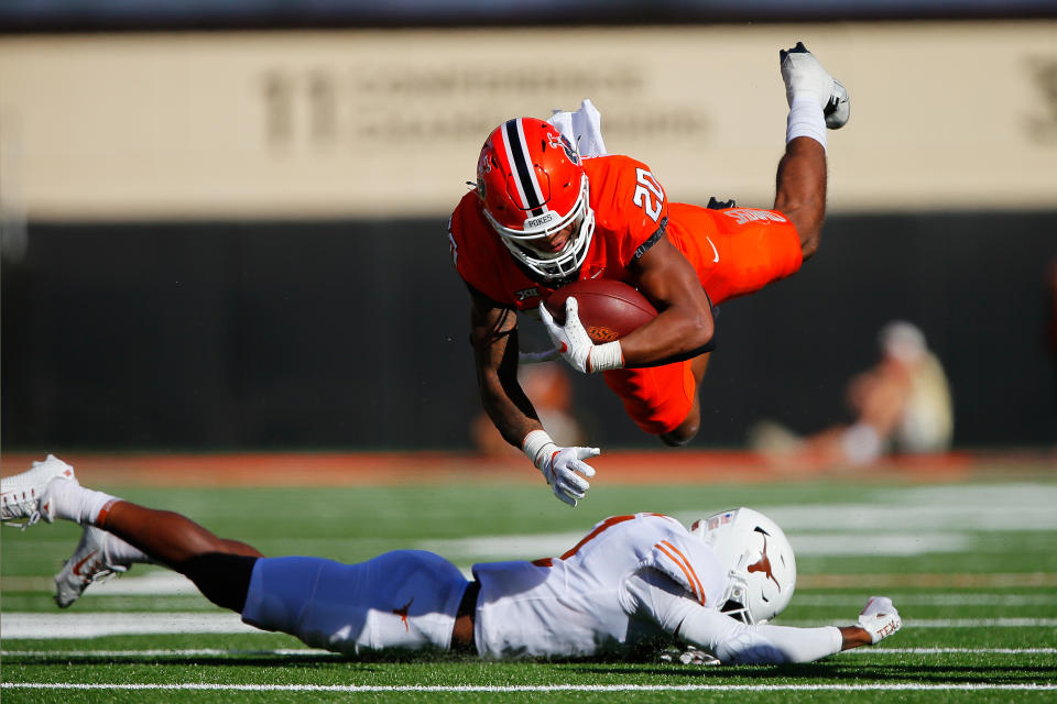 STILLWATER, OK - OCTOBER 22:  Running back Dominic Richardson #20 of the Oklahoma State Cowboys leaps over defensive lineman Justice Finkley #1 of the Texas Longhorns in the second quarter at Boone Pickens Stadium on October 22, 2022 in Stillwater, Oklahoma.  (Photo by Brian Bahr/Getty Images)