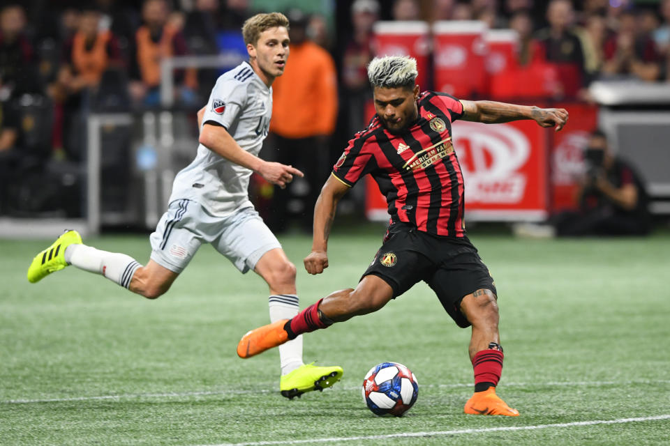 FILE - Atlanta United forward Josef Martinez (7) kicks a shot on goal as New England Revolution midfielder Scott Caldwell follows during round one of an MLS Cup playoff soccer game Saturday, Oct. 19, 2019, in Atlanta. Josef Martinez, the 2018 MVP and centerpiece of Atlanta United's rise to prominence in Major League Soccer, was released by the team on Wednesday, Jan. 18, 2023, and quickly signed a deal with Inter Miami. (AP Photo/John Amis, File)