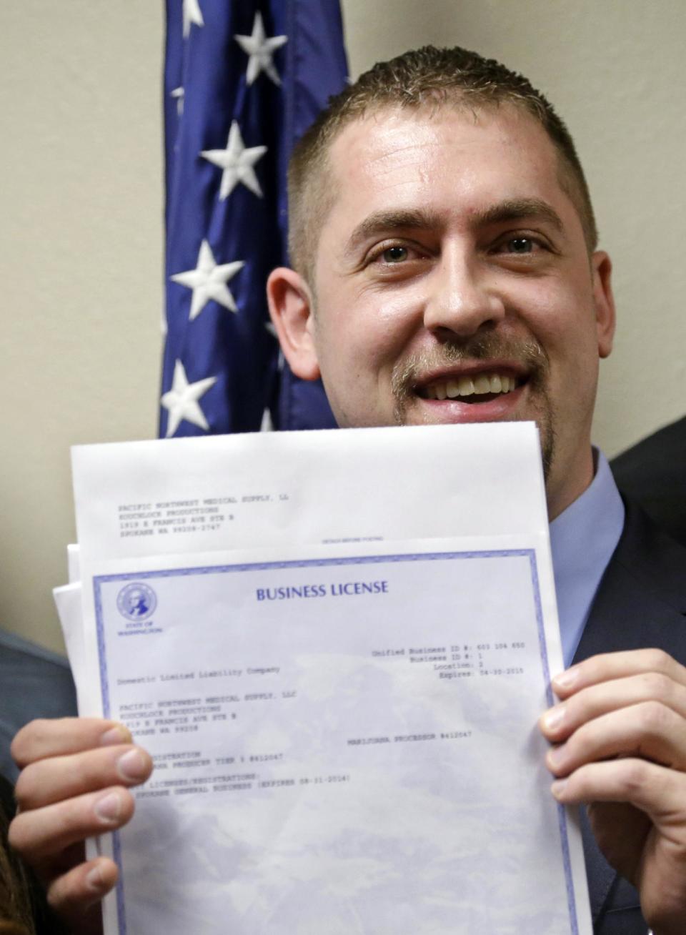 Sean Green displays his new Washington state legal marijuana license at a presentation Wednesday, March 5, 2014, in Olympia, Wash. Green, a medical marijuana dispensary operator from Spokane, was issued the producer-processor license under the state's recreational pot law at the Liquor Control Board meeting. (AP Photo/Elaine Thompson)