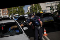 A local police stops a vehicle at a checkpoint in Madrid, Spain, Monday, Sept. 21, 2020. Police in the Spanish capital and its surrounding towns are stopping people coming in and out of working-class neighborhoods that have been partially locked down to stem Europe's fastest coronavirus spread. (AP Photo/Bernat Armangue)