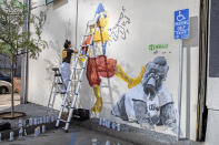 Ground Floor Murals artist Signe Ditona works on a mural of the San Diego Chicken mascot stomping on the Phillie Phanatic mascot in downtown San Diego, Monday, Oct. 17, 2022. The San Diego Padres and the Philadelphia Phillies are tied 1-1 in the baseball NL Championship Series. (Adriana Heldiz/The San Diego Union-Tribune via AP)