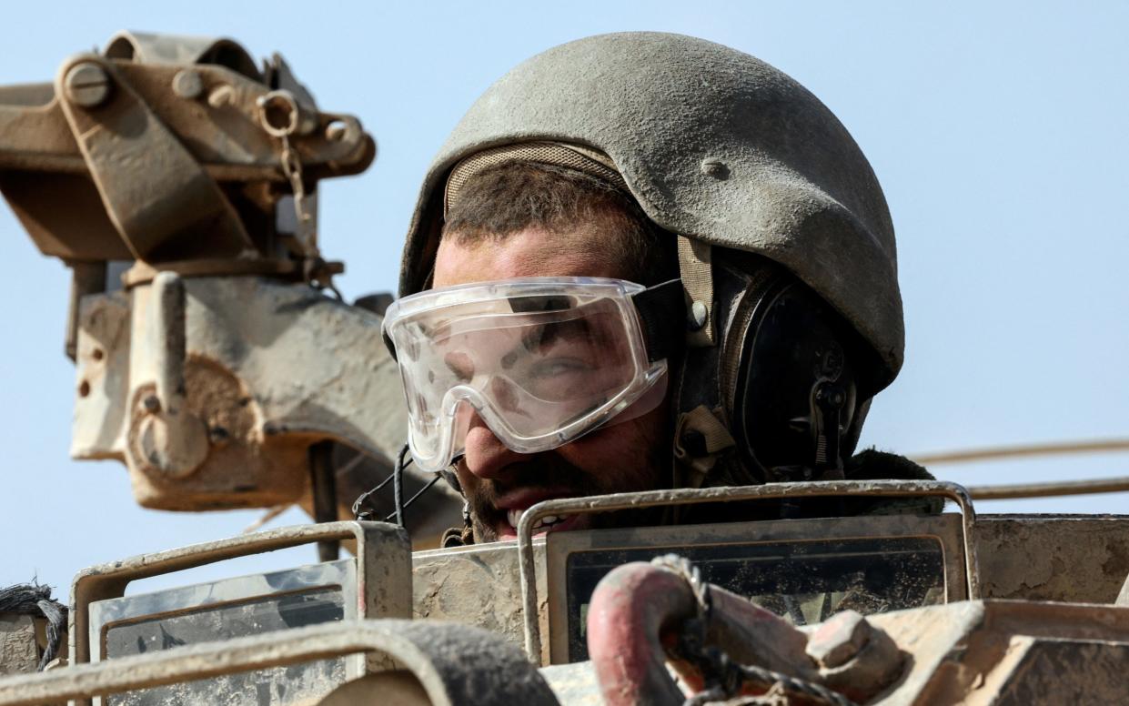 An Israeli soldier looks out from a tank near Israel's border with the Gaza Strip, in southern Israel