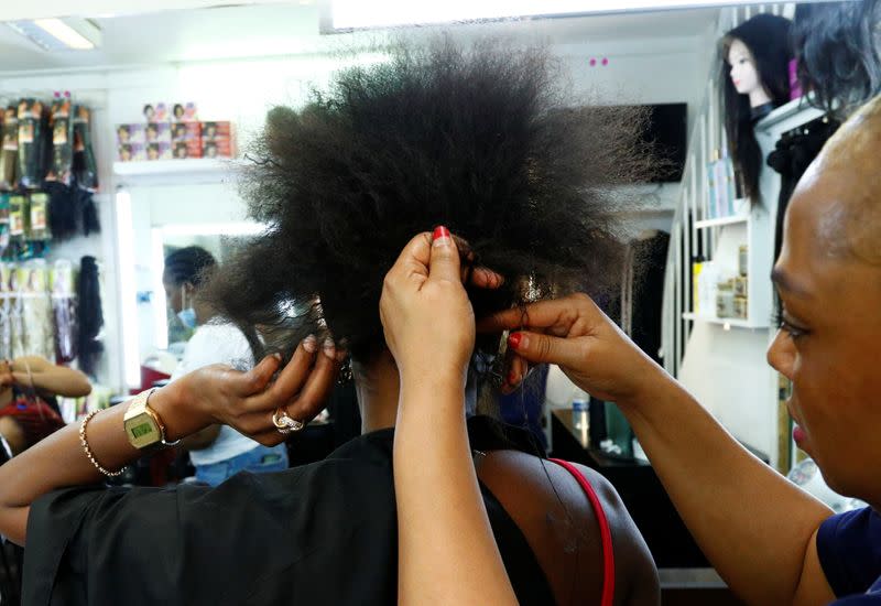 A hairdresser braids the hair of a client in a hair salon at the Matonge gallery in Brussels