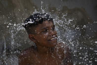A youth cools off in a water fountain at Madureira Park amid a heat wave in Rio de Janeiro, Brazil, Wednesday, Nov. 15, 2023. (AP Photo/Bruna Prado)