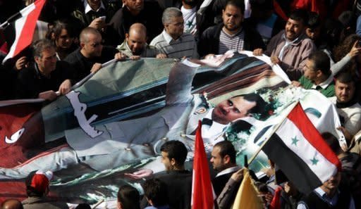 Syrian's hold a huge image of President Bashar al-Assad during a rally in his support in the capital in Damascus on November 13. Turkey on Sunday called on the international community for a united response to stop the bloodshed in Syria and summoned the Syrian envoy to condemn attacks on its diplomatic missions by pro-regime protesters
