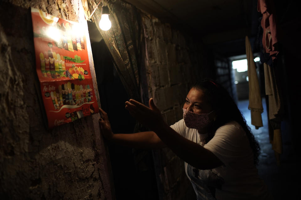 Informal worker Tassiana Nascimento Costa, who made a living hawking bottled water and sodas to tourists before the coronavirus pandemic hit, shows off a poster displaying the frozen treats she now sells to residents, posted inside the occupied building where she lives, in Rio de Janeiro, Brazil, Thursday, March 11, 2021. More than 6.5 million Brazilian women exited the workforce during the pandemic, dropping their participation rate below 48% - the least in more than a decade, according to official data published this month. (AP Photo/Silvia Izquierdo)