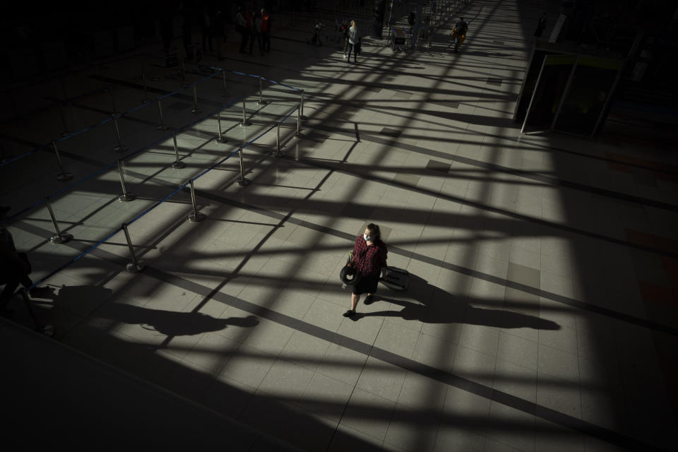 A passenger walks through an empty terminal at Ezeiza International Airport in Buenos Aires, Argentina, Monday, March 23, 2020. Most flights have been canceled to help stop the spread of the new coronavirus. (AP Photo/Victor R. Caivano)