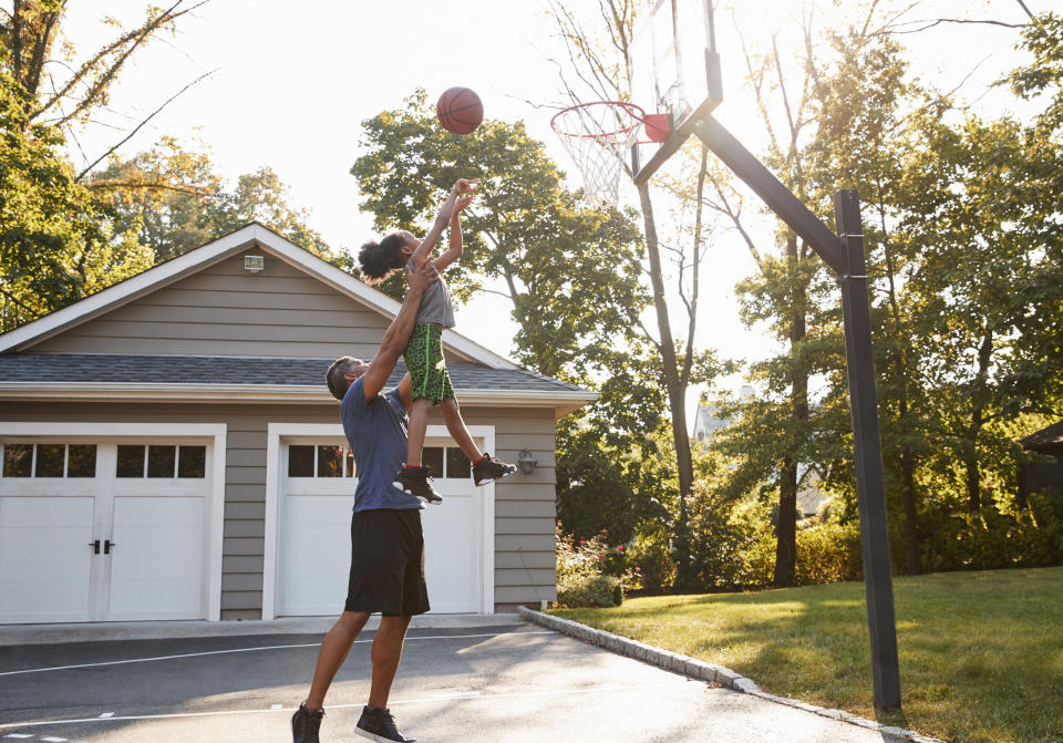 Father And Son Playing Basketball On Driveway At Home