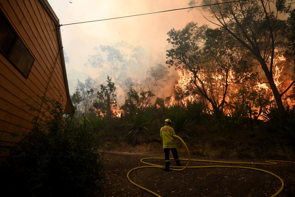 A firefighter on the ground hosing a blaze at Mangrove Mountain on Friday. Source: AAP