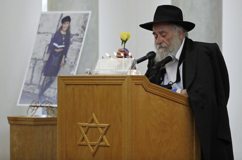 FILE - In this April 29, 2019 file photo, Yisroel Goldstein, Rabbi of Chabad of Poway, holds a yellow rose as he speaks at the funeral for Lori Kaye, who is pictured at left, in Poway, Calif. Prosecutors say John T. Earnest opened fire during the Passover service at the synagogue on April 27, killing Kaye and injuring three people, including the rabbi. A preliminary hearing for Earnest begins Thursday, Sept. 18, 2019, in state court and is expected to last up to two days. (AP Photo/Gregory Bull, File)