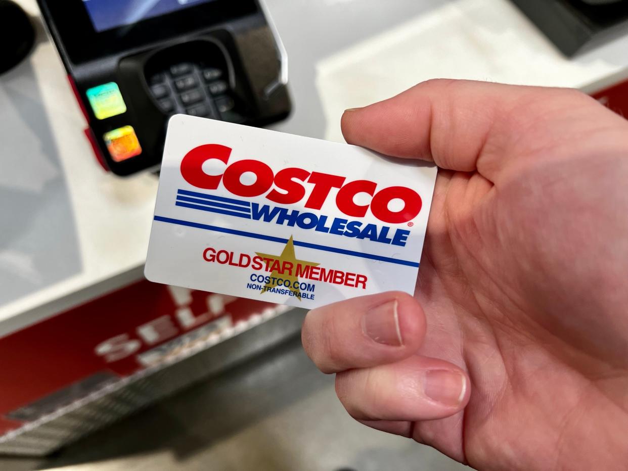 A hand holding a Costco gold-star membership card