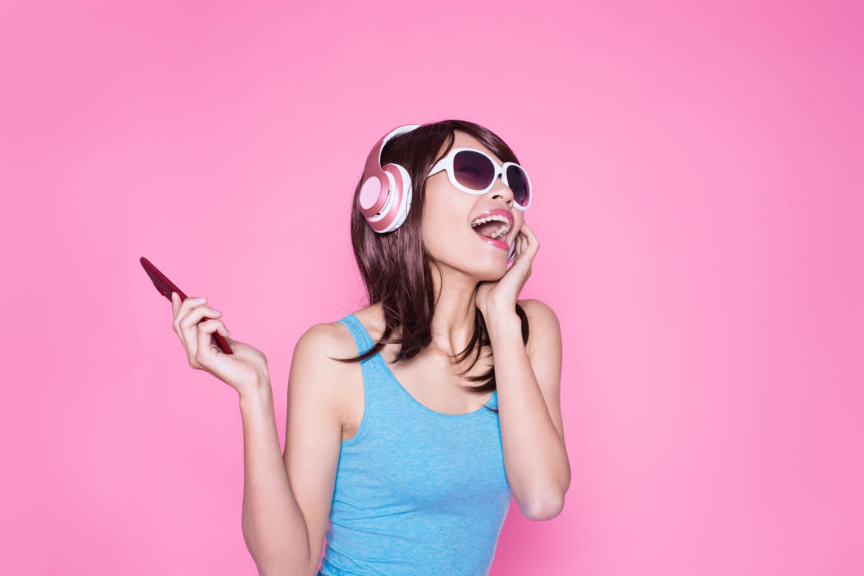 A young woman listens to music on her smartphone.