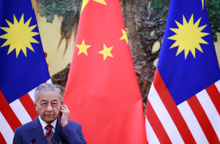 Malaysia's Prime Minister Mahathir Mohamad adjusts his earphones during a news conference with China's Premier Li Keqiang (not pictured) at the Great Hall of the People in Beijing, China, August, 20, 2018. How Hwee Young/Pool via REUTERS