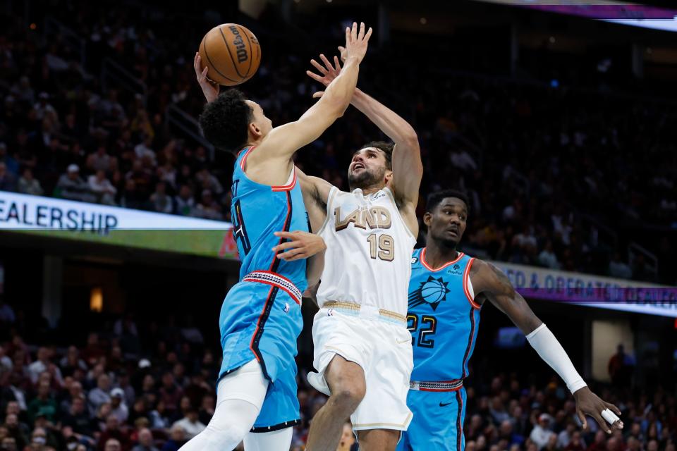 Cleveland Cavaliers guard Raul Neto (19) shoots between Phoenix Suns guard Landry Shamet and center Deandre Ayton during the second half of an NBA basketball game, Wednesday, Jan. 4, 2023, in Cleveland. (AP Photo/Ron Schwane)