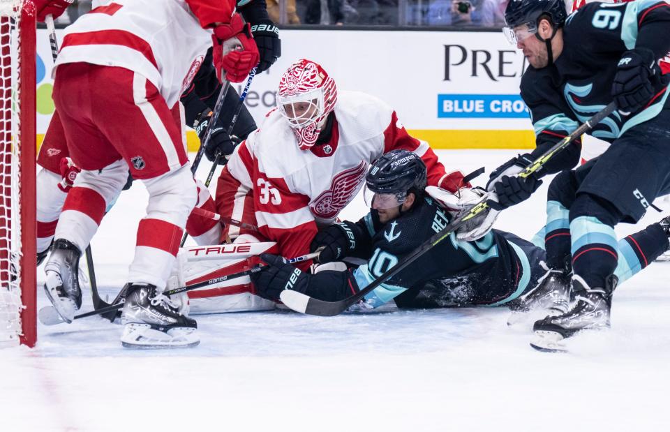 Seattle Kraken forward Matty Beniers (10) and Detroit Red Wings goalie Ville Husso (35) fight for a loose puck in front of the goal during the first period at Climate Pledge Arena in Seattle on Saturday, Feb. 18, 2023.