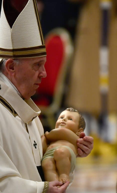 El papa Francisco celebra la misa de Navidad llevando una efigie del niño Jesús en el Vaticano el 24 de diciembre de 2021 (AFP/Filippo MONTEFORTE)