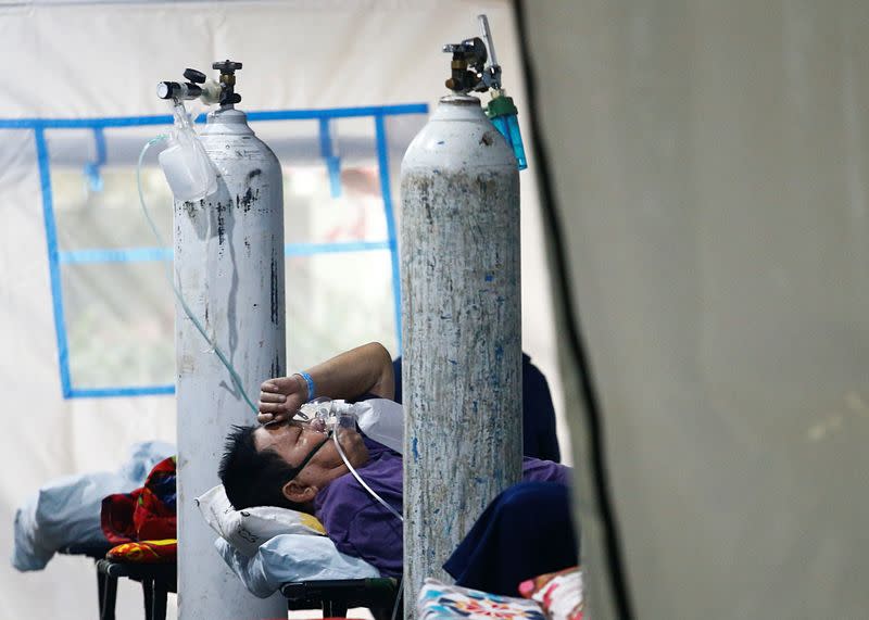 A patient suffering from the coronavirus disease (COVID-19) breaths with a non-rebreather mask in an emergency tent at a hospital in Jakarta