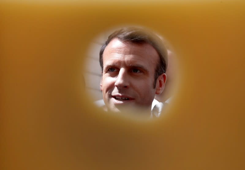 FILE PHOTO: French President Emmanuel Macron is pictured through a piece of cheese as he attends the annual May Day ceremony during which French food products are displayed at the Elysee Palace, in Paris