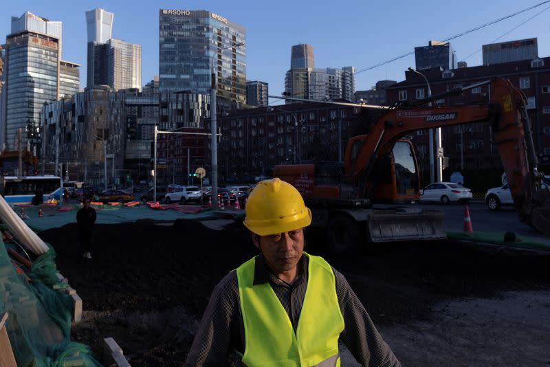 A worker walks across a construction site in the Central Business District, ahead of the opening of the National People's Congress (NPC) in Beijing