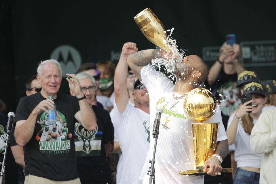 Milwaukee Bucks' P.J. Tucker drinks Champagne as he holds the NBA Championship Trophy during a parade celebrating the basketball team's NBA Championship win, Thursday, July 22, 2021, in Milwaukee. (AP Photo/Aaron Gash)