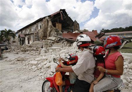 A family riding a motorcycle looks at a damaged church after an earthquake in the tourist town of Lobok, Bohol October 17, 2013. REUTERS/Erik De Castro