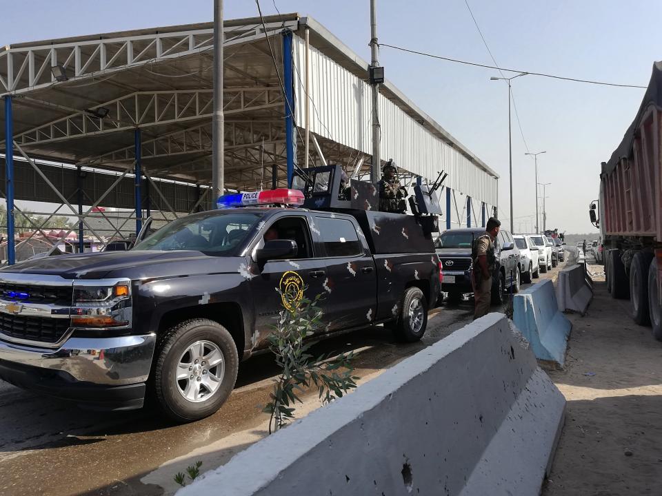 Security forces reopen a checkpoint after the explosion outside Karbala, Iraq, Saturday, Sept. 21, 2019. A bomb exploded on a minibus packed with passengers outside the Shiite holy city of Karbala Friday night, killing and wounding civilians, Iraqi security officials said. (AP Photo/Hadi Mizban)