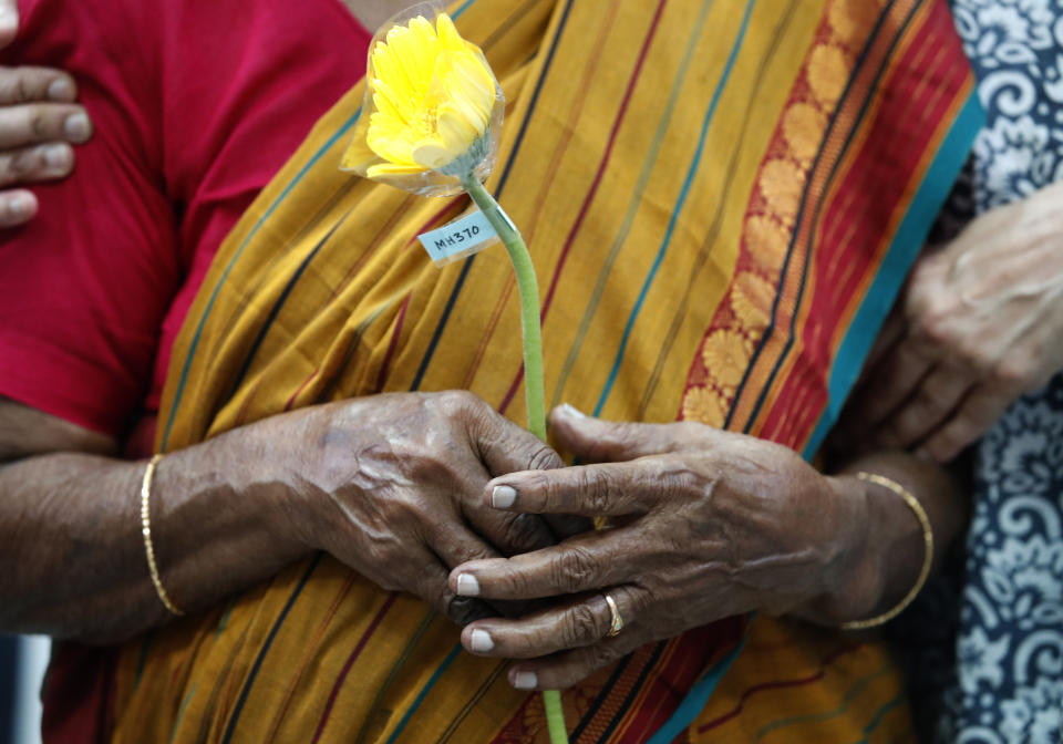 A family member of a passenger on board of the missing Malaysia Airlines Flight 370 holds a flower during the tenth annual remembrance event at a shopping mall, in Subang Jaya, outskirts of Kuala Lumpur, Malaysia, Sunday, March 3, 2024. (AP Photo/FL Wong)