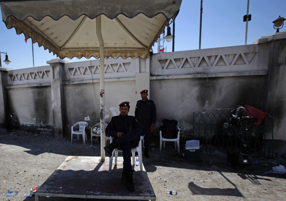 Policemen stand guard in front of a police station after is was attached by angry Bahraini anti-government protesters in Sitra, Bahrain, Tuesday, May 6, 2014. Bahraini police have confronted attackers who tried to firebomb a police post in a largely Shiite community in the tiny Gulf island nation, authorities said Tuesday. (AP Photo/Hasan Jamali)