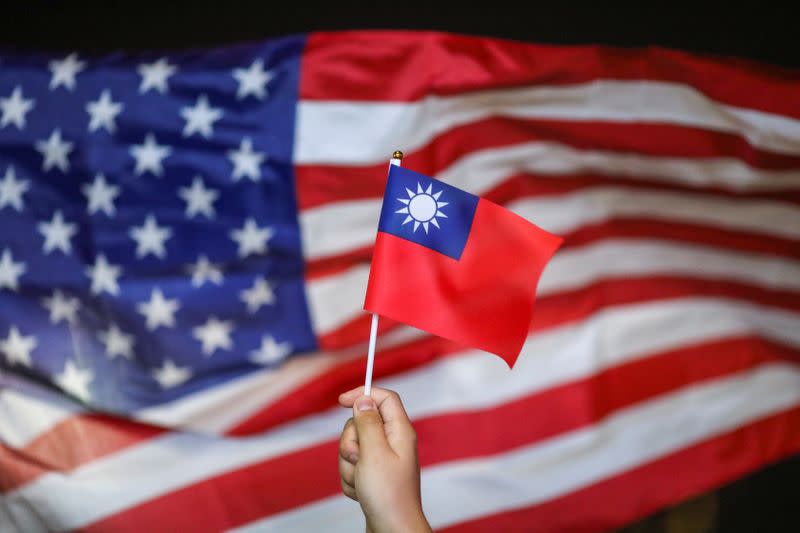 An anti-government protester holds a Taiwan national flag as an U.S. flag flutters in the background during a demonstration to celebrate Taiwan's National Day at the Harbour city in Tsim Sha Tsui district, in Hong Kong