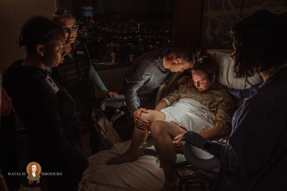 Group gathers for support during a home birth at night with city lights in the background