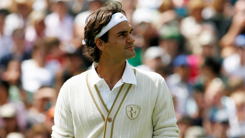 Roger Federer wears a vest with his logo as he looks up at the crowd at Wimbledon.