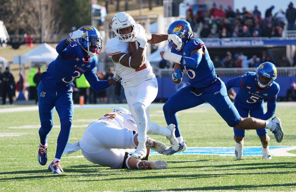 Texas running back Roschon Johnson fights off Kansas cornerback Ra'Mello Dotson and linebacker Taiwan Berryhill during Saturday's game. Johnson left with a leg injury, but it wasn't believed to be serious.