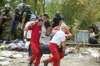 Recuers carry a man after clashes between Macedonian police forces and migrants trying to cross the border from Greece into Macedonia near the town of Gevgelija, Macedonia, on August 22, 2015