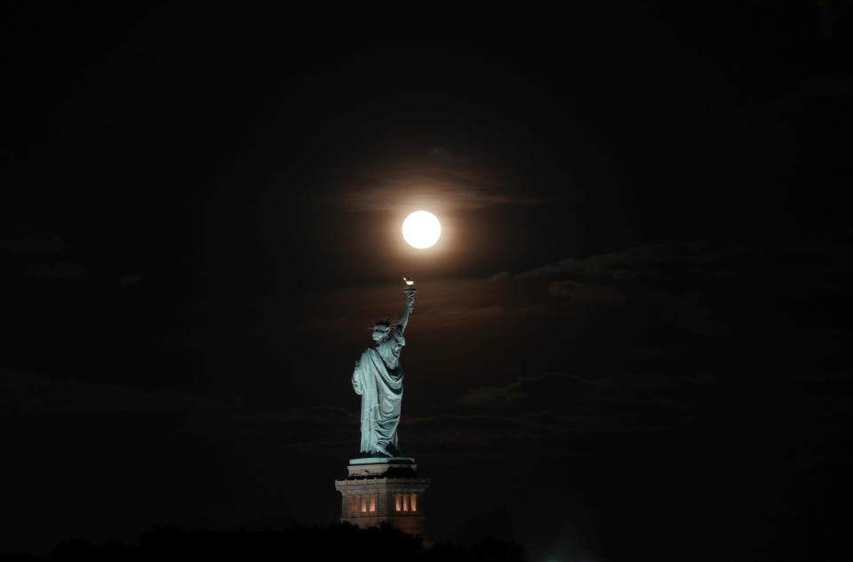 The full Harvest Moon rises above the Statue of Liberty in New York City on September 13, 2019 as seen from Jersey City, New Jersey. / Credit: Gary Hershorn / Getty Images