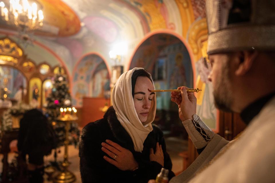 An Orthodox priest offers the holy communion to a woman during Christmas church service in Kostyantynivka, Ukraine (Copyright 2020 The Associated Press. All rights reserved)