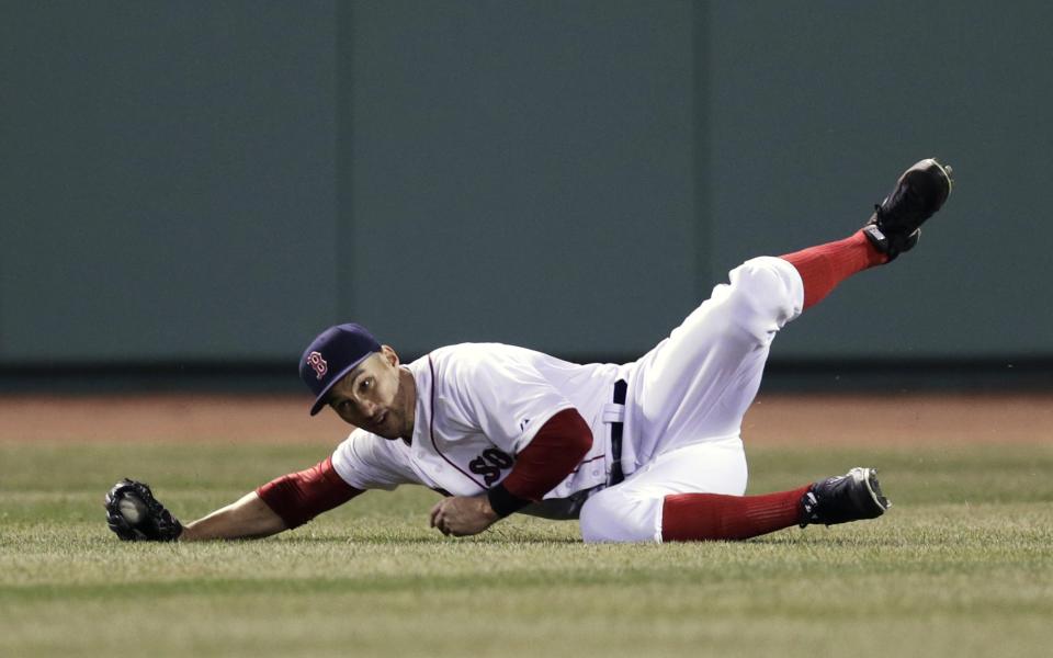 Boston Red Sox center fielder Grady Sizemore rolls as he makes the catch on a sacrifice fly by Texas Ranger Mitch Moreland, which scored Adrian Beltre, during the fourth inning of a MLB baseball game at Fenway Park, Monday, April 7, 2014, in Boston.(AP Photo/Charles Krupa)