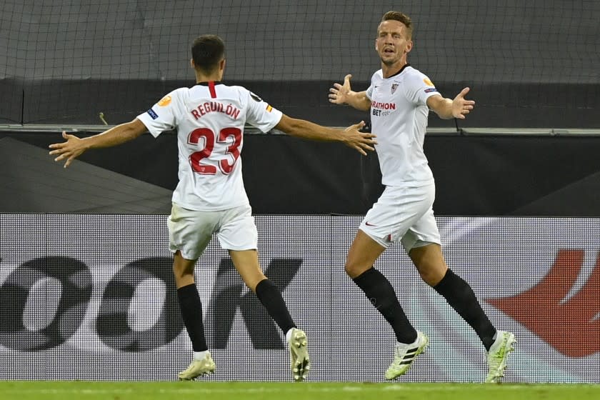 Sevilla's Luuk de Jong, right, celebrates with his teammate Sergio Reguilon after he scored his side's second goal during an Europa League semifinal match between Sevilla and Manchester United, in Cologne, Germany, Sunday, Aug. 16, 2020. (AP Photo/Martin Meissner, Pool)
