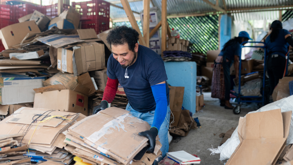 Worker sorting cardboard boxes at recycling center - Miguel Serrano Ruiz/iStockphoto