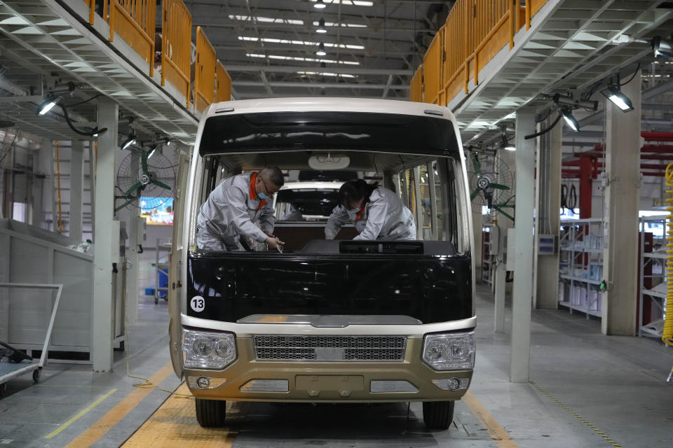Workers assemble wires on a dashboard of a minibus at a Tenglong Automobile Co. manufacturing factory during a media-organized tour in Xiangyang in central China's Hubei Province on May 10, 2023. China's manufacturing and consumer spending are weakening after a strong start to 2023 after anti-virus controls ended. (AP Photo/Andy Wong)