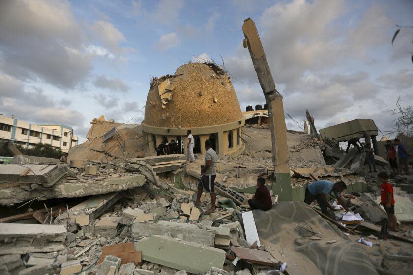 People stand outside a mosque destroyed in an Israeli air strike in Khan Younis, Gaza Strip, Sunday, Oct.8, 2023. The Hamas militants broke out of the blockaded Gaza Strip and rampaged through nearby Israeli communities, taking captives, while Israel's retaliation strikes leveled buildings in Gaza. (AP Photo/Yousef Masoud)