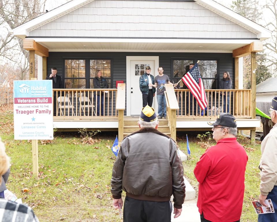 Dave Loop of American Legion Post 97 in Adrian presents U.S. Air Force veteran Joshua Traeger with a flag for his new home during Habitat for Humanity of Lenawee County's dedication ceremony Friday, Nov. 11, 2022, in Adrian. Habitat built the house with the intent of having it go to a veteran.