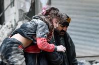 Residents carry an injured child from the rubble of a collapsed building following an earthquake in the town of Jandaris, in the countryside of Syria’s northwestern city of Afrin in the rebel-held part of Aleppo province (AFP via Getty Images)