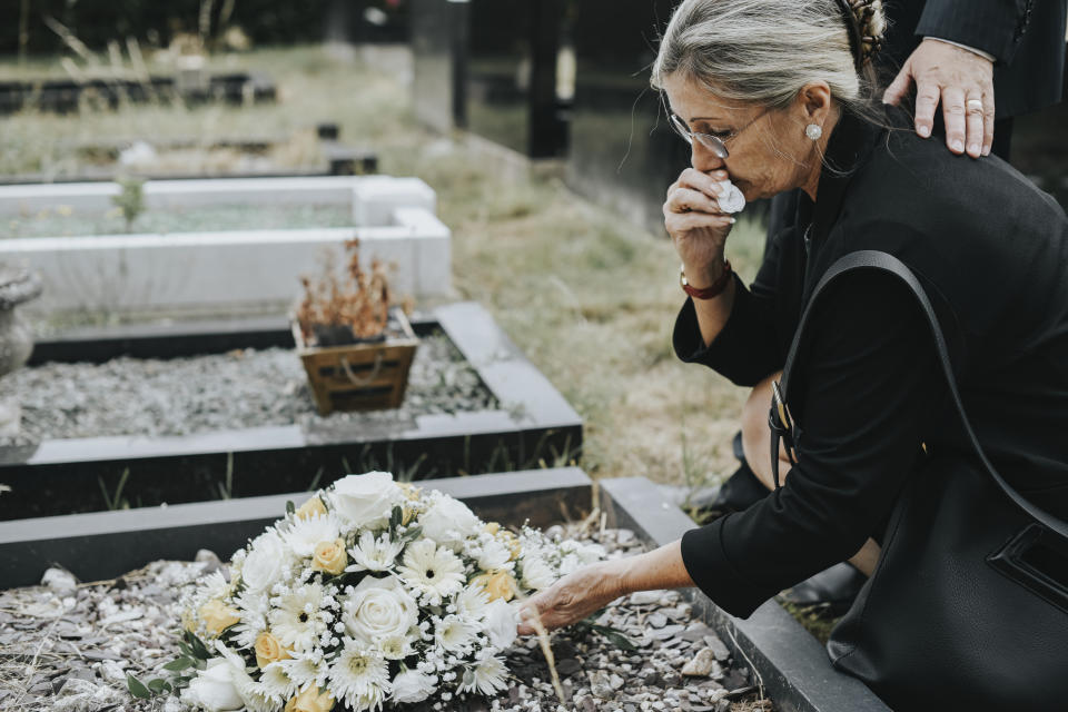 Old woman laying flowers on a grave